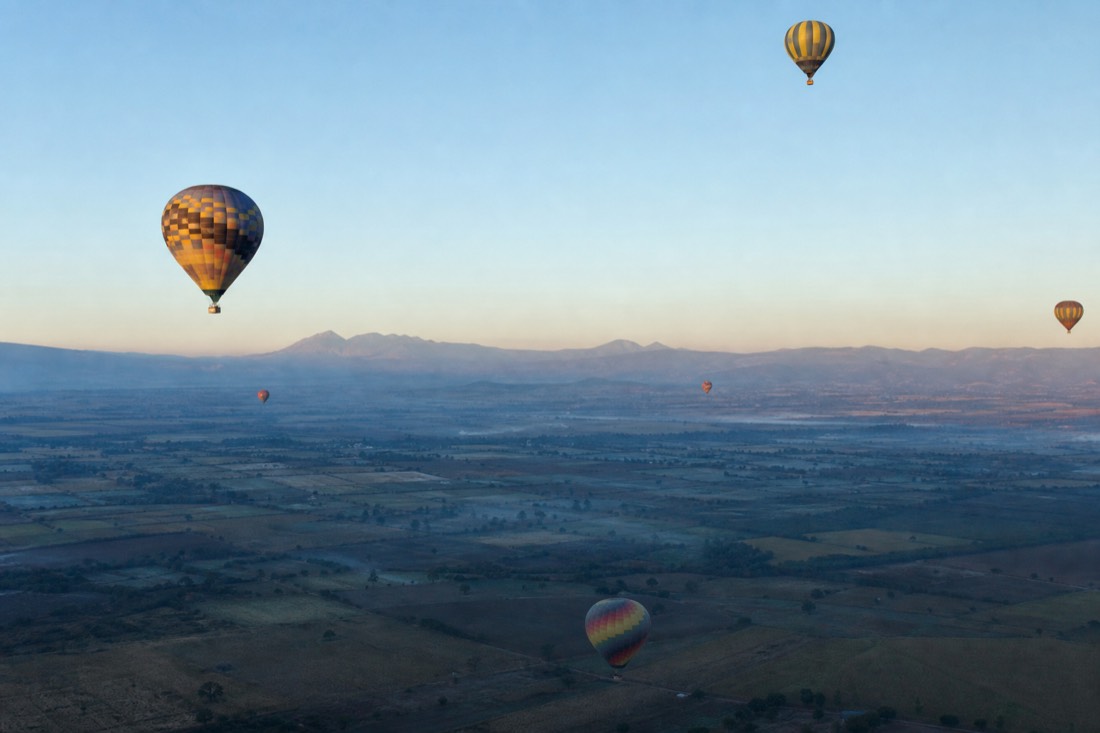 Other hot air balloons catching first light above the Teotihuacan valley while the ground is still in shadow